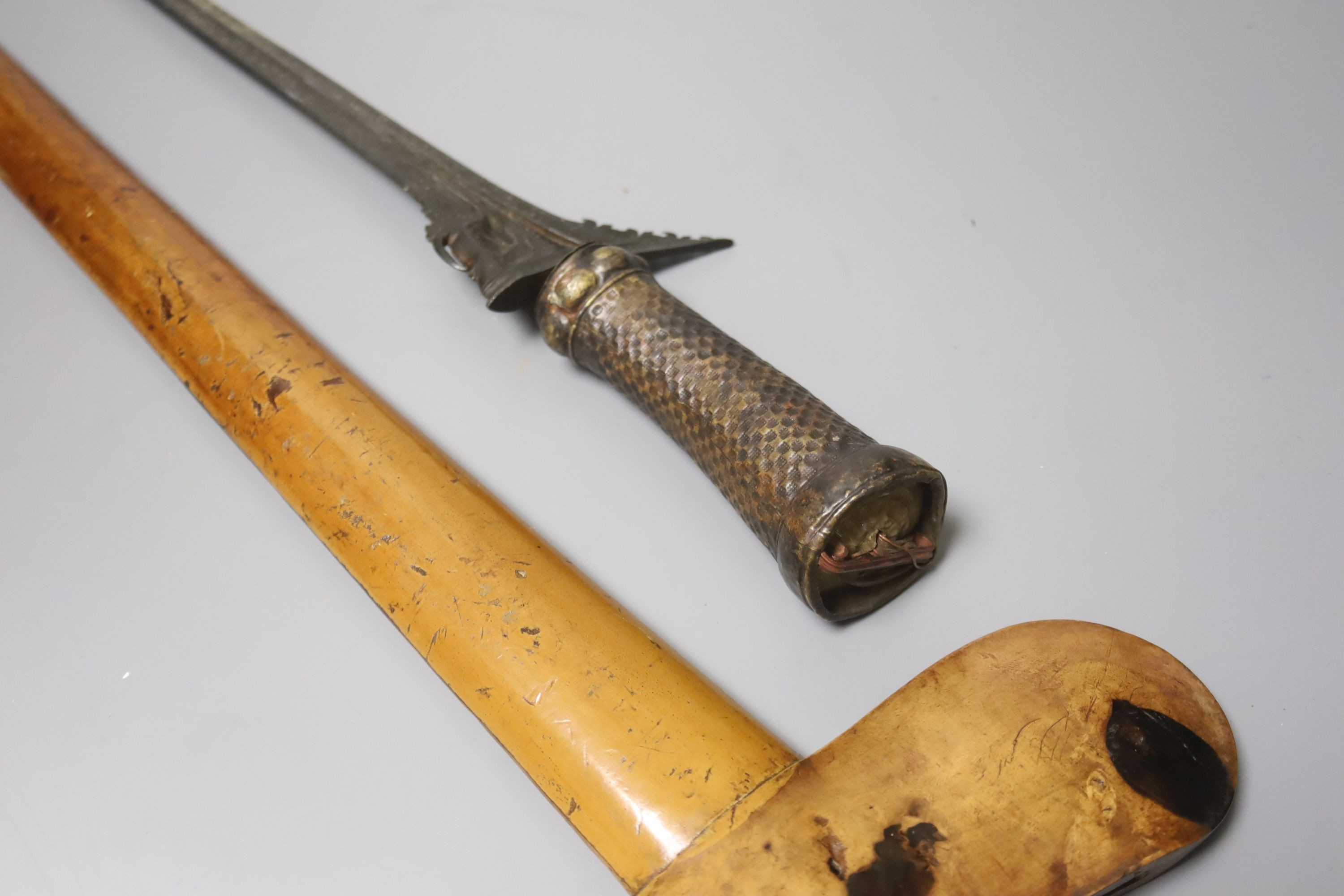 An Indonesian dagger kris, 19th century, earlier black and silver-coloured watered blade, brass hilt, wooden scabbard, blade 33cms